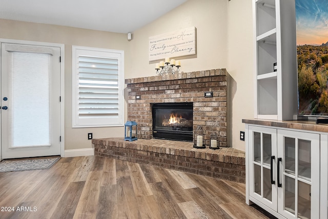 living room with a fireplace, wood-type flooring, a chandelier, and lofted ceiling