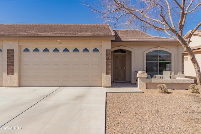 view of front of house with driveway, a tile roof, a garage, and stucco siding