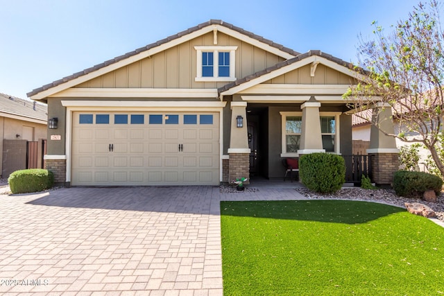 craftsman-style house with stucco siding, a front lawn, a garage, stone siding, and decorative driveway