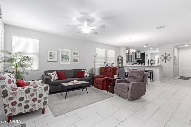 living room with visible vents, arched walkways, and ceiling fan with notable chandelier