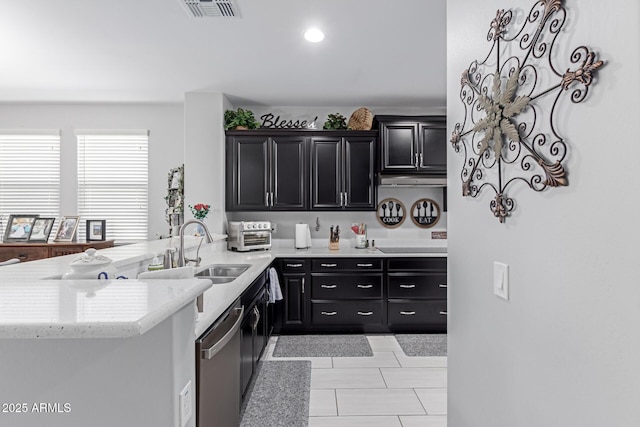 kitchen with dark cabinetry, visible vents, a peninsula, a sink, and dishwasher