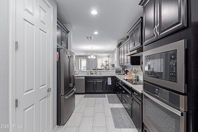 kitchen featuring recessed lighting, a sink, light countertops, under cabinet range hood, and appliances with stainless steel finishes