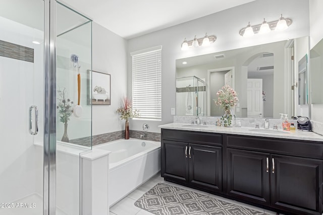 full bathroom with a bath, a shower stall, double vanity, and a sink