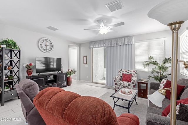 living room with arched walkways, visible vents, and ceiling fan