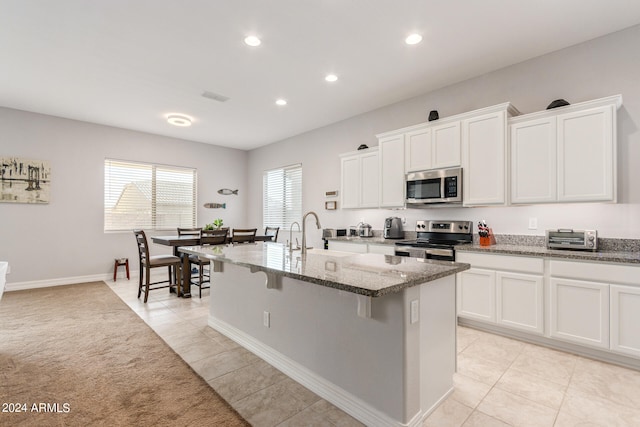 kitchen featuring white cabinets, stone countertops, light tile patterned floors, and stainless steel appliances