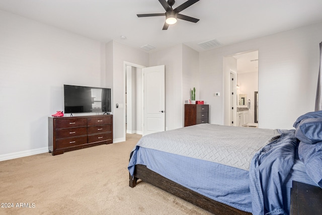 bedroom featuring ceiling fan, connected bathroom, and light colored carpet