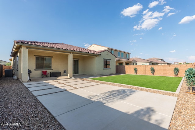 back of property with central air condition unit, a patio, and a yard