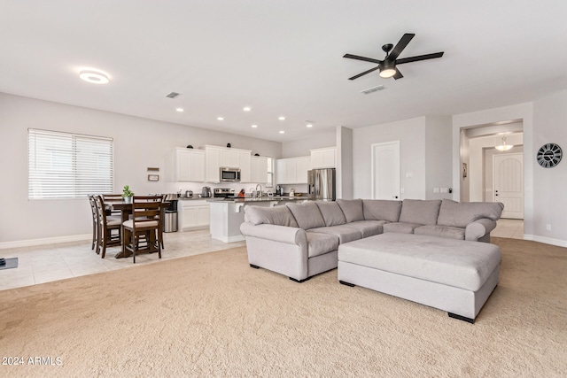 living room with light carpet, sink, and ceiling fan