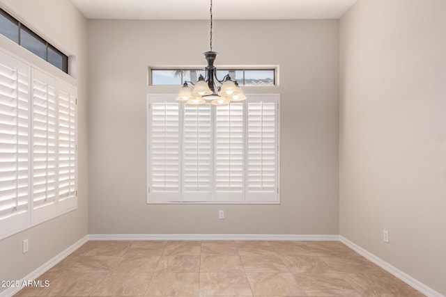 tiled spare room with a chandelier