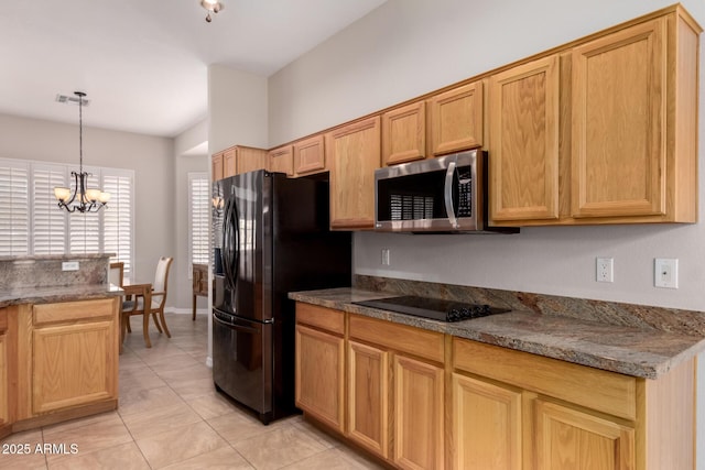 kitchen with light tile patterned floors, appliances with stainless steel finishes, a notable chandelier, stone countertops, and decorative light fixtures