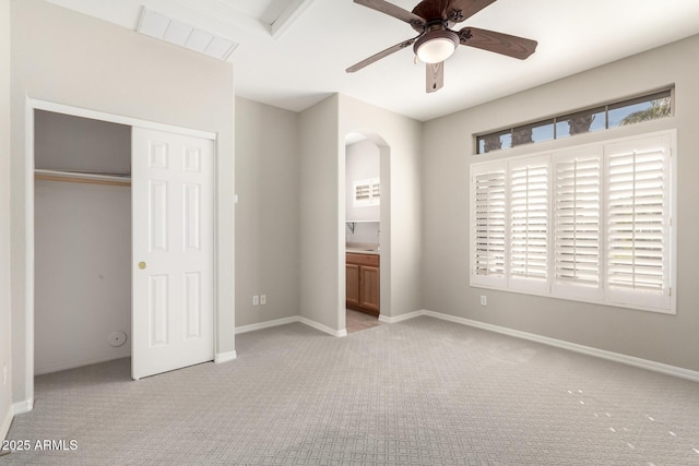 unfurnished bedroom with ceiling fan, ensuite bathroom, and light carpet