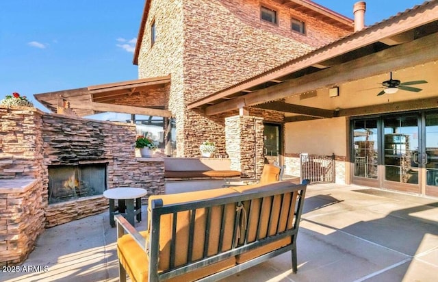 view of patio / terrace with ceiling fan, an outdoor stone fireplace, and french doors