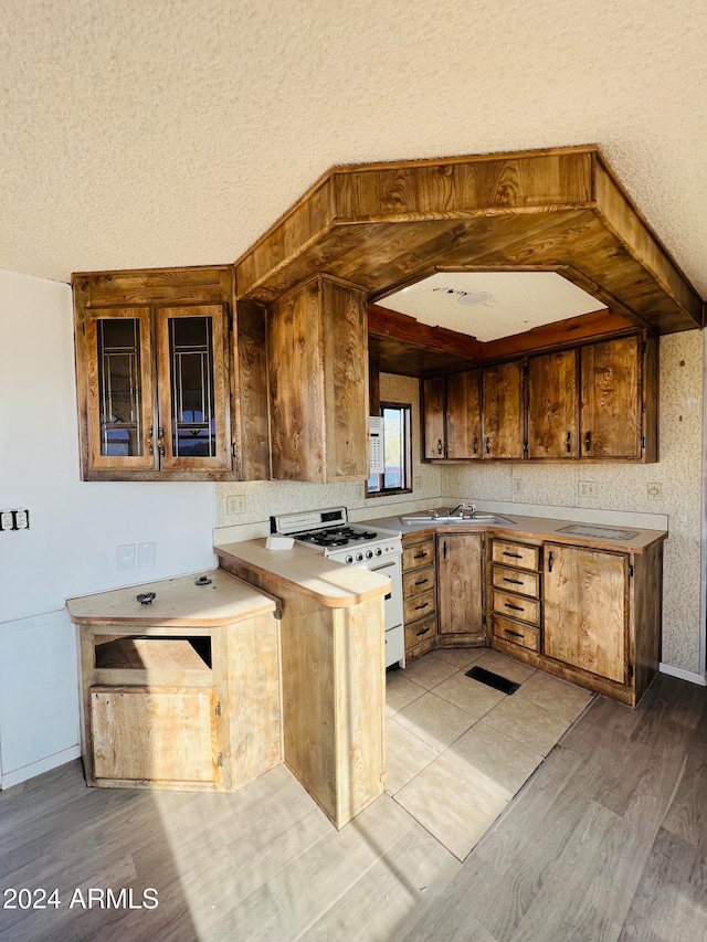 kitchen with a textured ceiling, white range oven, light hardwood / wood-style flooring, and sink