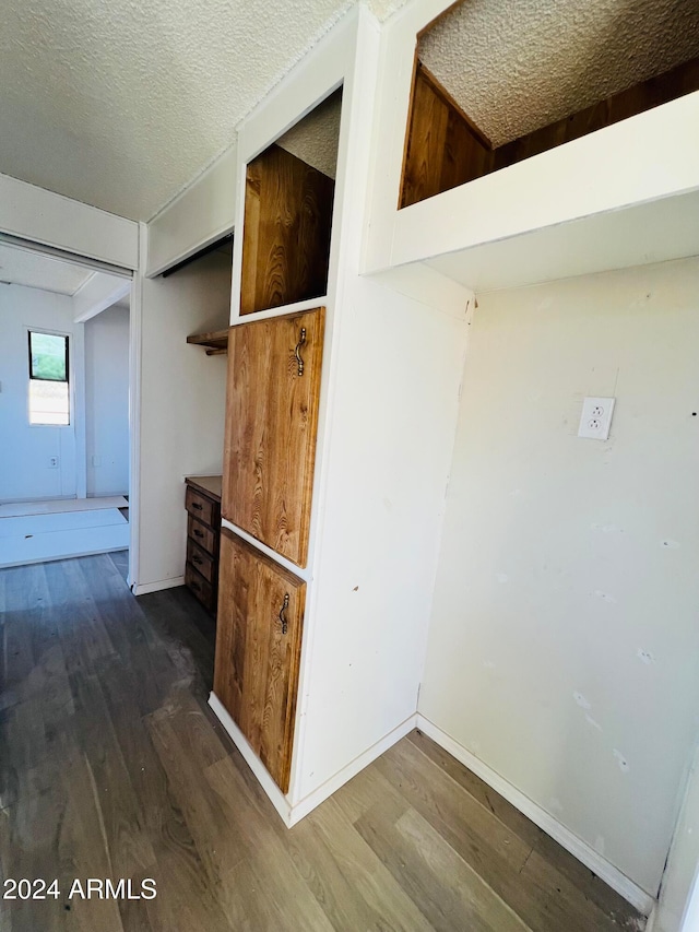 hallway with dark wood-type flooring and a textured ceiling