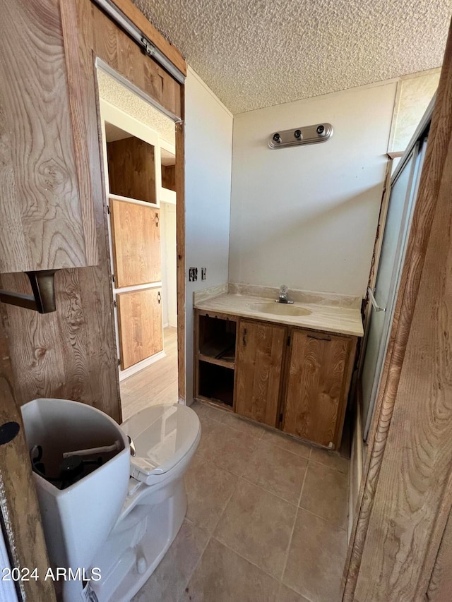 bathroom with tile patterned floors, vanity, a textured ceiling, and toilet