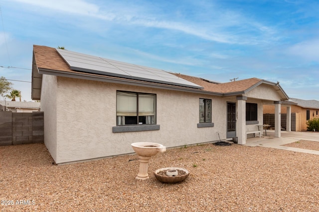 rear view of property with a patio and solar panels