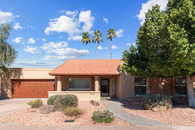 view of front facade with stucco siding, concrete driveway, a tiled roof, and an attached garage