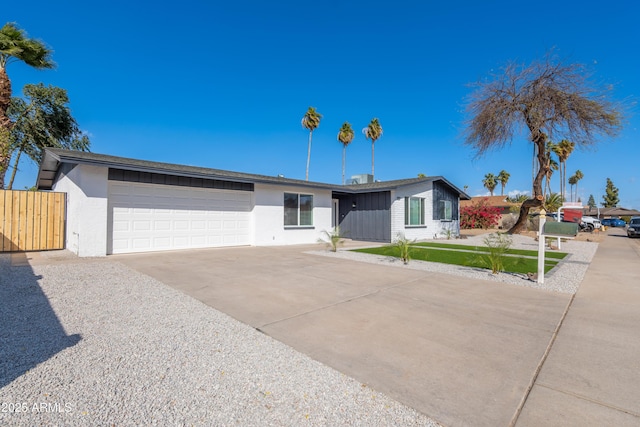 view of front of house with a garage, concrete driveway, fence, and stucco siding