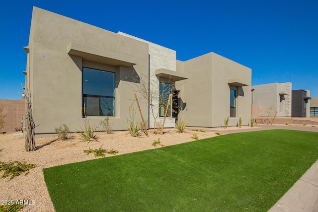 exterior space with a front lawn, fence, and stucco siding