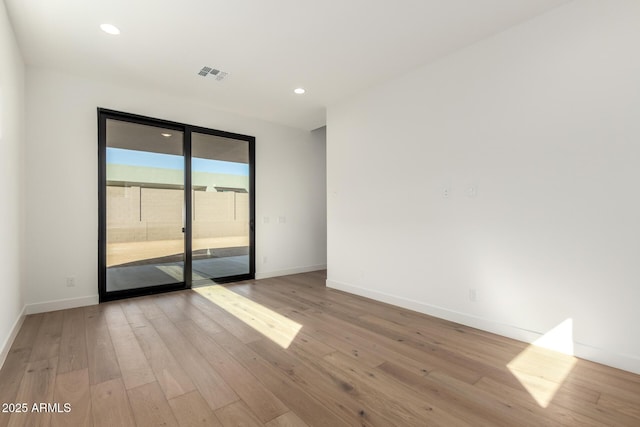 empty room with hardwood / wood-style flooring, recessed lighting, baseboards, and visible vents