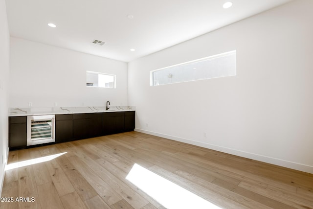 bar featuring a sink, recessed lighting, wine cooler, light wood-style floors, and baseboards