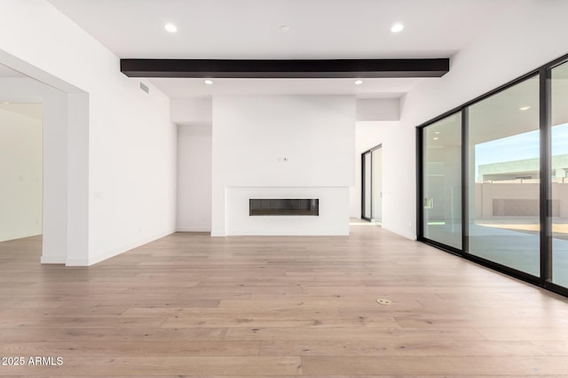 unfurnished living room with a glass covered fireplace, beam ceiling, recessed lighting, and light wood finished floors