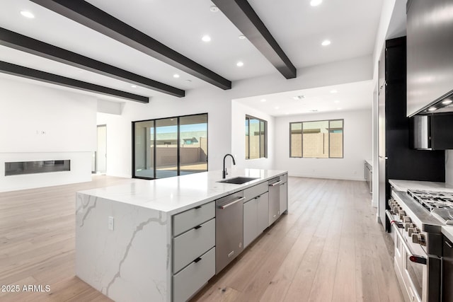 kitchen with a spacious island, beam ceiling, a sink, stainless steel appliances, and open floor plan