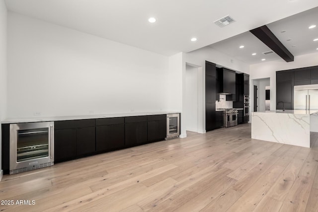 unfurnished living room featuring beverage cooler, visible vents, light wood-style flooring, and beam ceiling