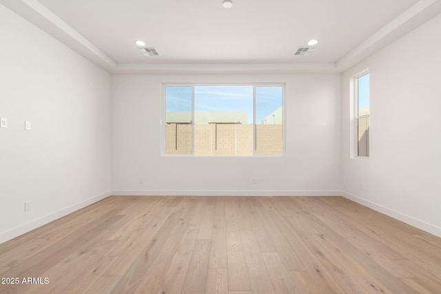 empty room featuring light wood finished floors, visible vents, recessed lighting, and baseboards