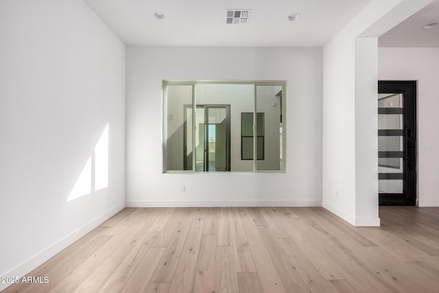 spare room featuring visible vents, baseboards, and wood finished floors