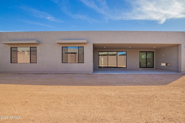 rear view of property featuring a patio and stucco siding