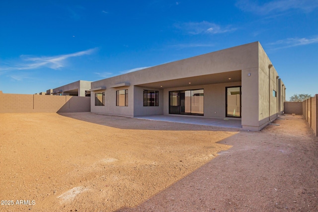 rear view of property featuring stucco siding, a patio, and a fenced backyard