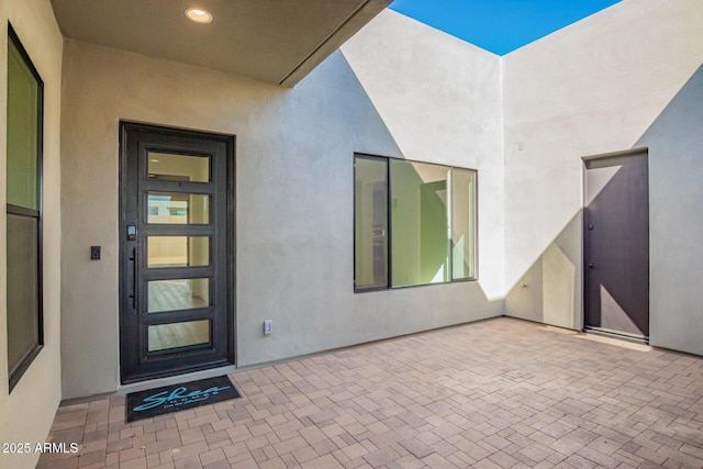 entrance to property featuring stucco siding and a patio area