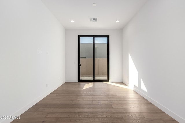 spare room with recessed lighting, visible vents, baseboards, and wood finished floors