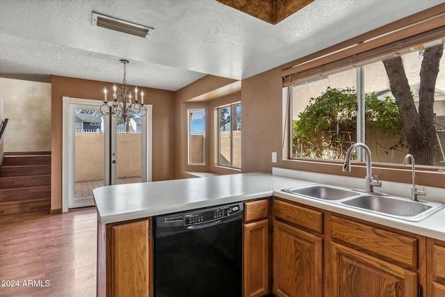 kitchen featuring kitchen peninsula, sink, light wood-type flooring, a textured ceiling, and black dishwasher