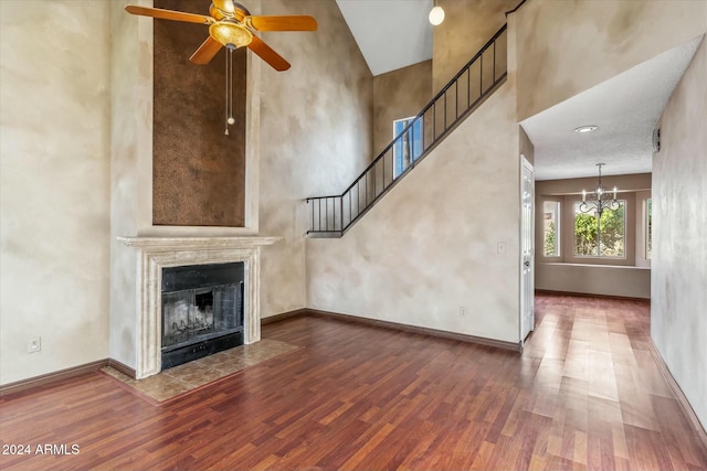 unfurnished living room featuring high vaulted ceiling, hardwood / wood-style floors, and ceiling fan with notable chandelier