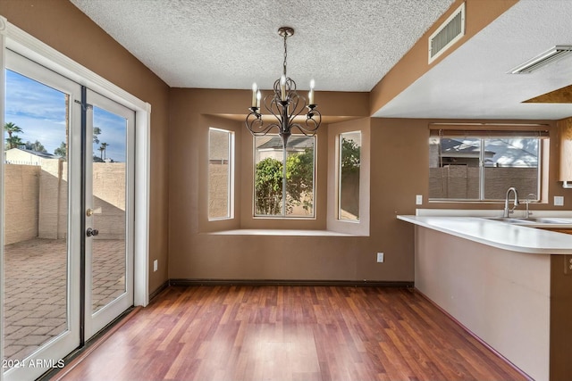 unfurnished dining area with sink, a healthy amount of sunlight, and an inviting chandelier