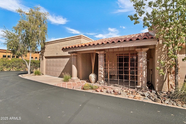 mediterranean / spanish house featuring a garage, a tiled roof, and stucco siding