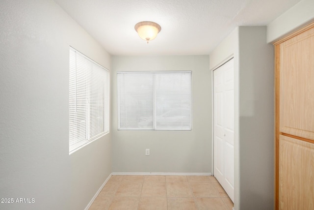 interior space with a wealth of natural light, baseboards, and light tile patterned floors