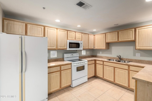 kitchen featuring white appliances, visible vents, a sink, and light brown cabinetry