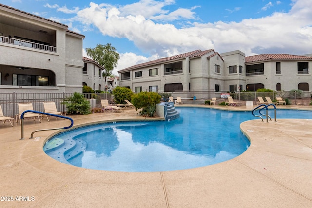 community pool featuring a residential view, a patio, and fence