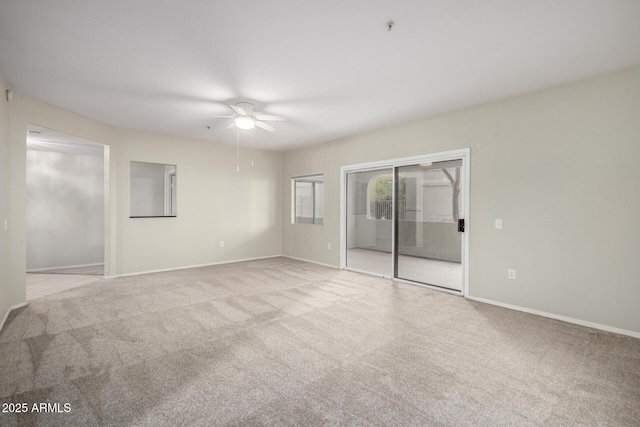 carpeted spare room featuring ceiling fan and baseboards