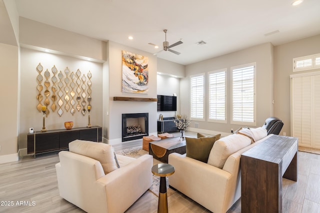 living area featuring visible vents, baseboards, recessed lighting, a fireplace, and light wood-style flooring