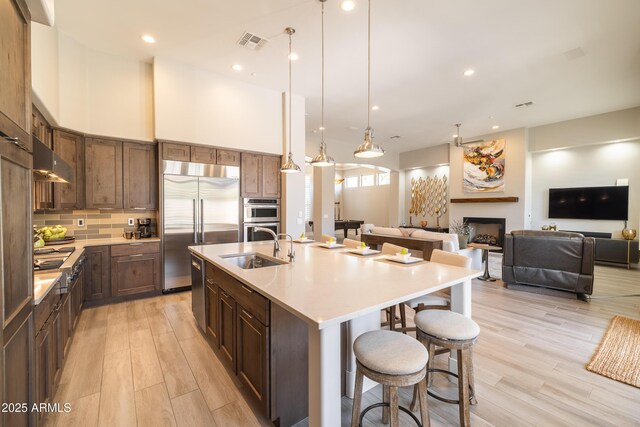 kitchen featuring a breakfast bar, a fireplace, a sink, appliances with stainless steel finishes, and backsplash