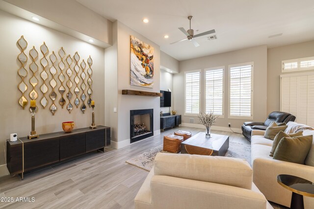 living room with light wood finished floors, visible vents, baseboards, recessed lighting, and a fireplace