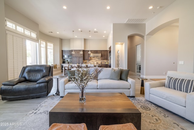 living room featuring visible vents, recessed lighting, arched walkways, light wood finished floors, and baseboards