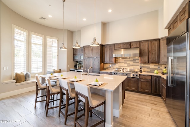 kitchen with tasteful backsplash, visible vents, under cabinet range hood, stainless steel appliances, and a sink