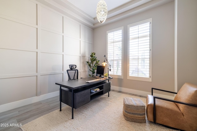 office space featuring a wealth of natural light, baseboards, light wood finished floors, and a decorative wall