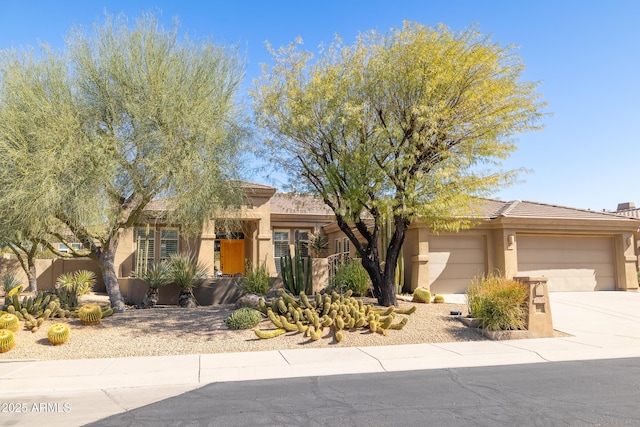 adobe home featuring stucco siding, concrete driveway, a garage, and fence