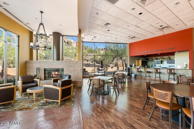 dining room with visible vents, a brick fireplace, wood finished floors, and an inviting chandelier